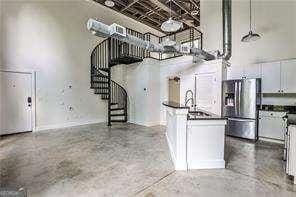 791 Wylie St SE Unit 404, Atlanta, GA 30316 - kitchen with stainless steel fridge with ice dispenser, dark countertops, a towering ceiling, white cabinetry, and hanging light fixtures