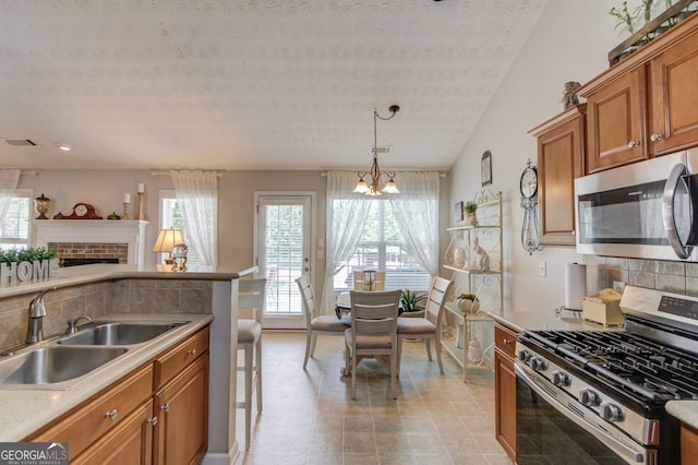 253 Lakeview Bend Cir, Jefferson, GA 30549 - kitchen featuring stainless steel appliances, brown cabinetry, healthy amount of natural light, a chandelier, and a textured ceiling