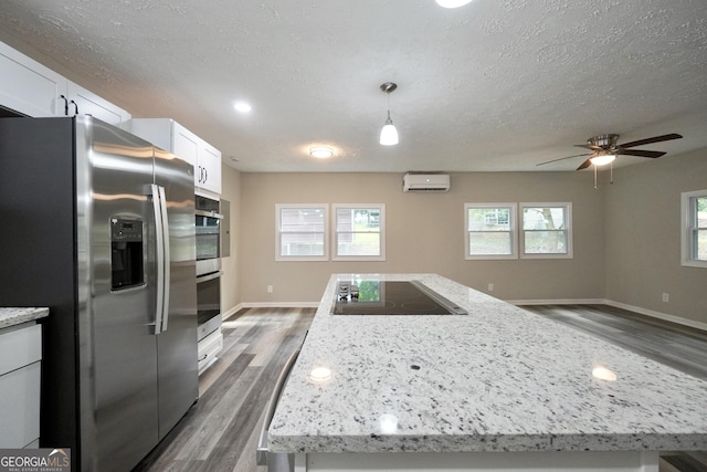 118 Turtle Cove Trwy, Monticello, GA 31064 - kitchen featuring appliances with stainless steel finishes, a kitchen island, dark wood-type flooring, a textured ceiling, and a wall unit AC