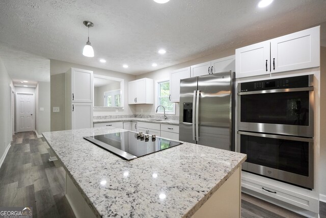 118 Turtle Cove Trwy, Monticello, GA 31064 - kitchen with stainless steel appliances, dark wood finished floors, white cabinets, a kitchen island, and light stone countertops