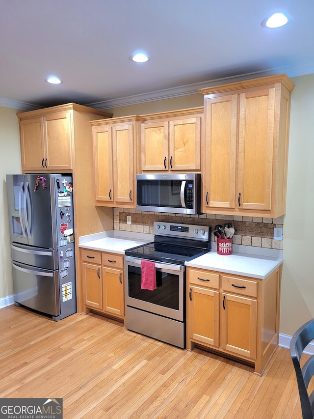 223 Overland Trl, Mcdonough, GA 30252 - kitchen featuring appliances with stainless steel finishes, crown molding, light countertops, light wood-style flooring, and decorative backsplash