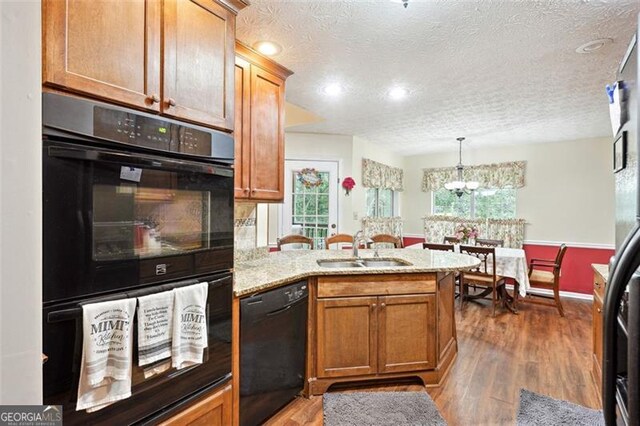 408 Victoria Place Dr, Locust Grove, GA 30248 - kitchen with black appliances, a peninsula, a textured ceiling, wood finished floors, and brown cabinets