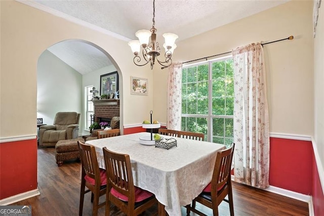 408 Victoria Place Dr, Locust Grove, GA 30248 - dining space with arched walkways, a chandelier, a fireplace, dark wood-style flooring, and a textured ceiling