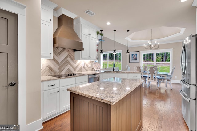 35 Cornish Creek Ln, Covington, GA 30014 - kitchen with custom range hood, stainless steel appliances, a peninsula, a raised ceiling, and a chandelier