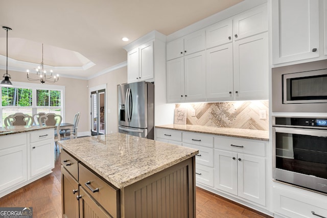 35 Cornish Creek Ln, Covington, GA 30014 - kitchen with appliances with stainless steel finishes, a chandelier, crown molding, decorative backsplash, and wood finished floors