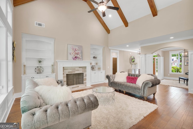 35 Cornish Creek Ln, Covington, GA 30014 - living area featuring high vaulted ceiling, ceiling fan, arched walkways, a tiled fireplace, and beam ceiling