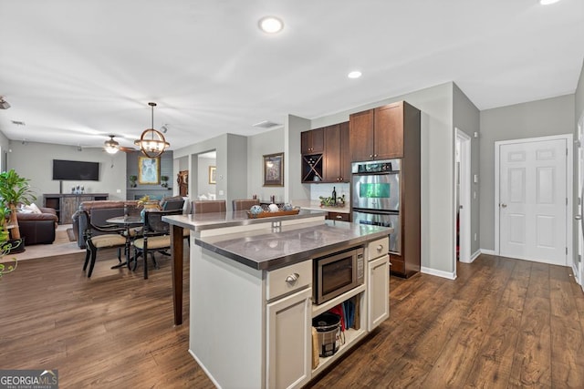 6131 Sparkling Cove Ln, Buford, GA 30518 - kitchen featuring appliances with stainless steel finishes, open floor plan, dark wood-style floors, a center island, and ceiling fan