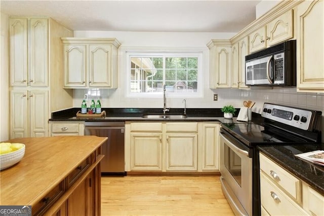 9685 Cone Ct, Roswell, GA 30075 - kitchen with appliances with stainless steel finishes, cream cabinetry, light wood-type flooring, and tasteful backsplash