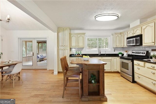 9685 Cone Ct, Roswell, GA 30075 - kitchen with stainless steel appliances, cream cabinets, french doors, dark countertops, and a textured ceiling