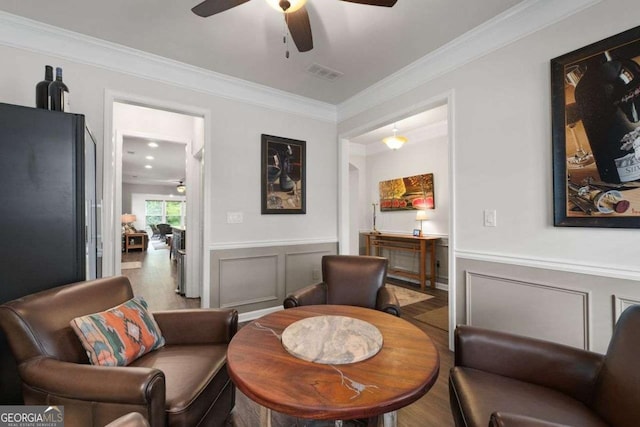 7430 Ramsgate Ct, Cumming, GA 30040 - living room with ceiling fan, ornamental molding, a wainscoted wall, wood finished floors, and a decorative wall