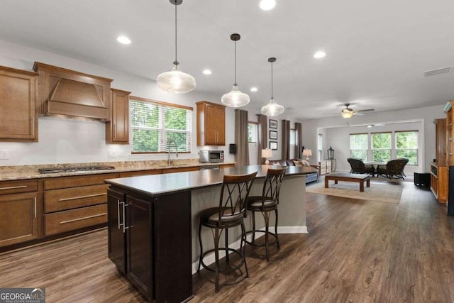 7430 Ramsgate Ct, Cumming, GA 30040 - kitchen featuring premium range hood, a kitchen island, open floor plan, stainless steel gas cooktop, and a breakfast bar area