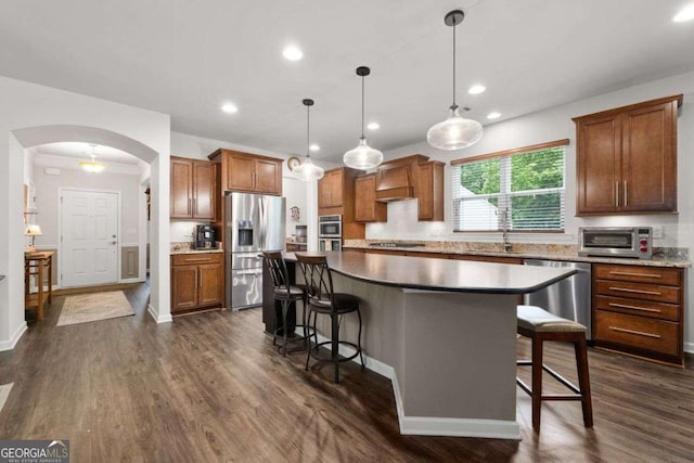 7430 Ramsgate Ct, Cumming, GA 30040 - kitchen featuring appliances with stainless steel finishes, arched walkways, a breakfast bar area, a kitchen island, and recessed lighting