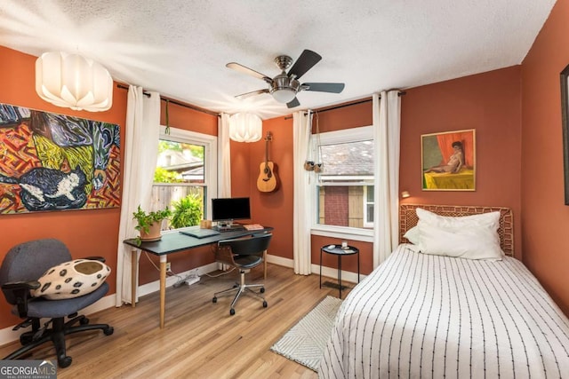 2468 Fallview Ter, Atlanta, GA 30344 - bedroom with multiple windows, wood finished floors, an office area, a textured ceiling, and ceiling fan