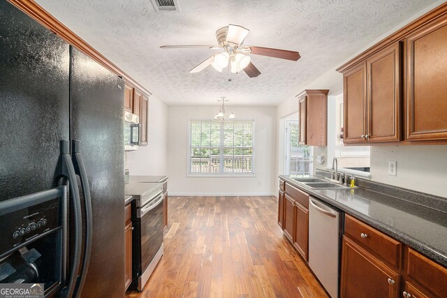 40 Browning Dr, Covington, GA 30016 - kitchen with appliances with stainless steel finishes, brown cabinets, light wood-type flooring, dark countertops, and a textured ceiling