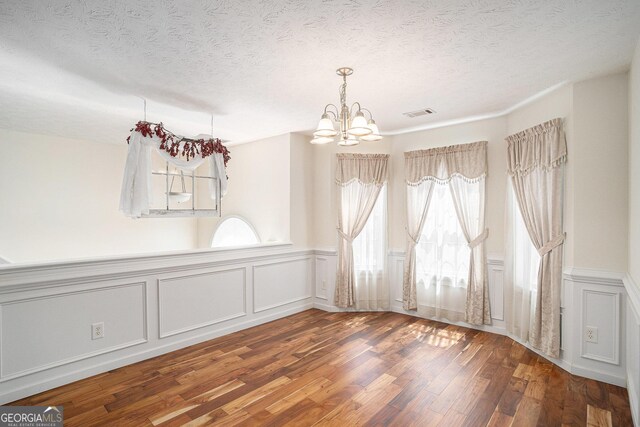 40 Browning Dr, Covington, GA 30016 - unfurnished dining area featuring a chandelier, healthy amount of natural light, a decorative wall, wood finished floors, and a textured ceiling