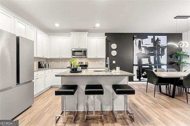 4992 Lower Elm, Atlanta, GA 30349 - kitchen with appliances with stainless steel finishes, white cabinetry, decorative backsplash, light wood-style flooring, and light stone countertops