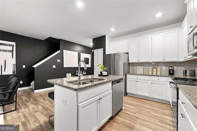 4992 Lower Elm, Atlanta, GA 30349 - kitchen featuring appliances with stainless steel finishes, light wood-style floors, a kitchen island with sink, white cabinetry, and recessed lighting