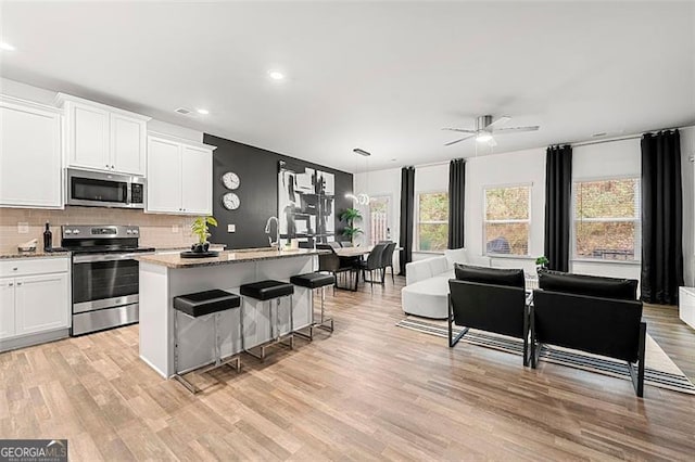 4992 Lower Elm, Atlanta, GA 30349 - kitchen with appliances with stainless steel finishes, a kitchen island with sink, healthy amount of natural light, light wood-style flooring, and recessed lighting