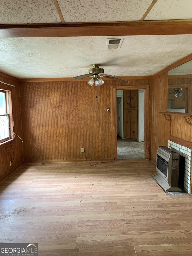 2712 Maple Rd SE, Rome, GA 30161 - unfurnished living room with light wood-type flooring, wood walls, a ceiling fan, heating unit, and a textured ceiling