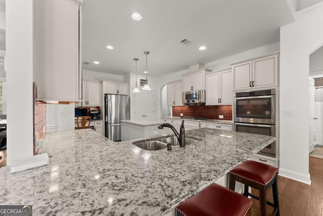 6460 Valley Crossing Way, Cumming, GA 30028 - kitchen with stainless steel appliances, arched walkways, dark wood-style floors, light stone countertops, and recessed lighting
