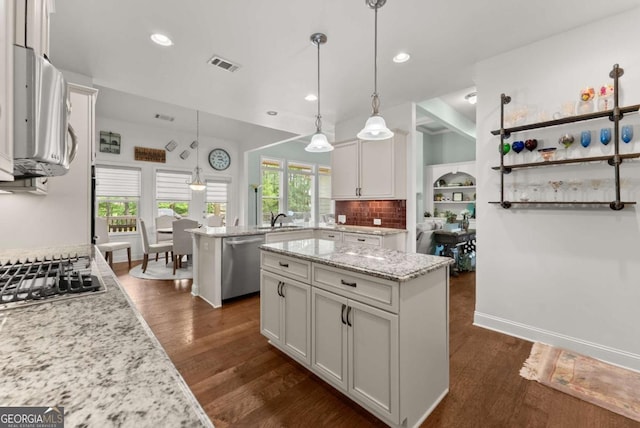 6460 Valley Crossing Way, Cumming, GA 30028 - kitchen featuring stainless steel appliances, a center island, white cabinetry, backsplash, and light stone countertops
