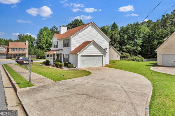 7770 Hana Ct, Jonesboro, GA 30236 - traditional-style house with a garage, concrete driveway, a front lawn, and a chimney