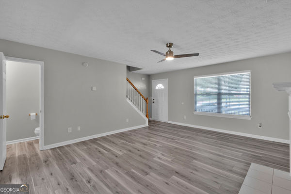 7770 Hana Ct, Jonesboro, GA 30236 - unfurnished living room with stairway, wood finished floors, and ceiling fan