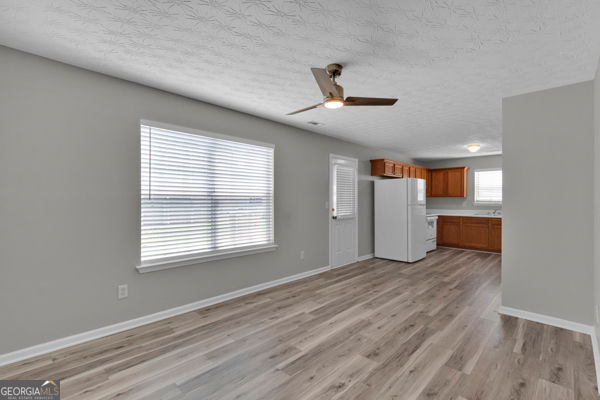 7770 Hana Ct, Jonesboro, GA 30236 - kitchen featuring freestanding refrigerator, brown cabinets, ceiling fan, a textured ceiling, and light wood-type flooring