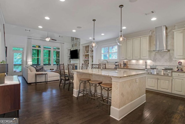 3467 Brookleigh Ln NE, Atlanta, GA 30319 - kitchen featuring wall chimney range hood, stainless steel gas cooktop, open floor plan, dark wood-style flooring, and light stone counters