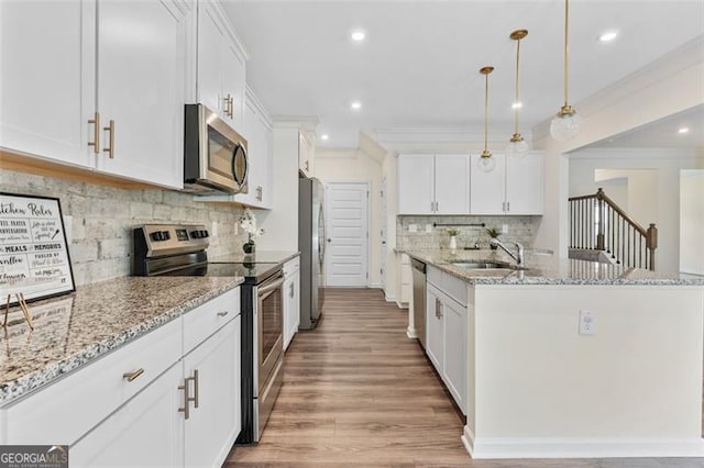 3390 Meadow Grass Dr, Dacula, GA 30019 - kitchen featuring stainless steel appliances, tasteful backsplash, a kitchen island with sink, light wood-style floors, and ornamental molding