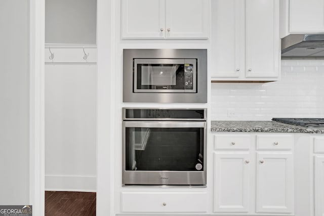 7043 Lancaster Xing, Flowery Branch, GA 30542 - kitchen with appliances with stainless steel finishes, white cabinetry, ventilation hood, stone counters, and wood finished floors