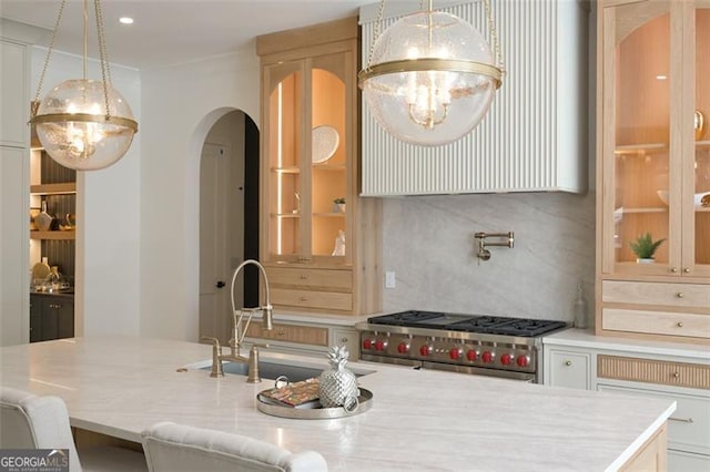 1312 Becket Dr NE, Brookhaven, GA 30319 - kitchen featuring range with two ovens, arched walkways, decorative light fixtures, light stone countertops, and a center island with sink
