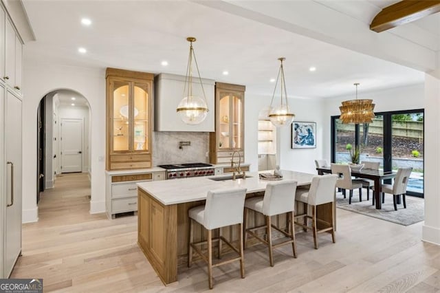 1312 Becket Dr NE, Brookhaven, GA 30319 - kitchen featuring decorative backsplash, light wood-style flooring, recessed lighting, an island with sink, and arched walkways