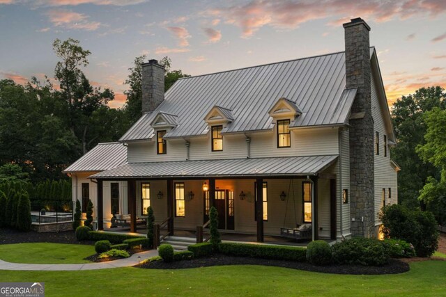 13365 Hopewell Rd, Alpharetta, GA 30004 - back of house with a chimney, covered porch, a yard, and a standing seam roof