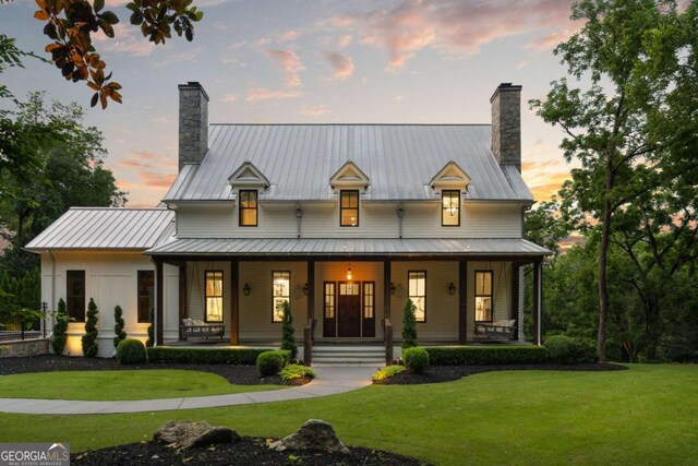13365 Hopewell Rd, Alpharetta, GA 30004 - back of property at dusk with a chimney, a porch, a standing seam roof, and a lawn