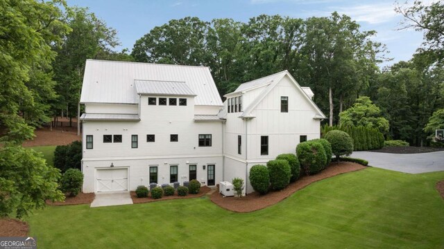 13365 Hopewell Rd, Alpharetta, GA 30004 - rear view of property featuring a lawn, a garage, a standing seam roof, and driveway