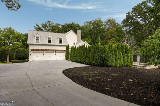 13365 Hopewell Rd, Alpharetta, GA 30004 - view of home's exterior featuring concrete driveway, a chimney, a garage, and view of wooded area