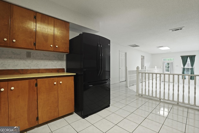 684 Frances Ln, Brooklet, GA 30415 - kitchen featuring freestanding refrigerator, brown cabinets, light tile patterned floors, light countertops, and a textured ceiling