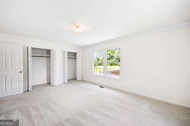 204 Old Oak Rd, Macon, GA 31216 - unfurnished bedroom with two closets, crown molding, carpet flooring, and a textured ceiling