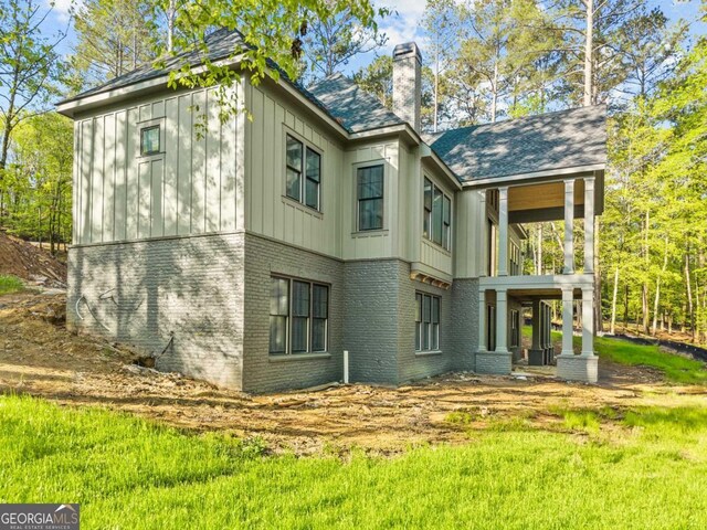 1281 Snug Harbor Dr, Greensboro, GA 30642 - back of house featuring brick siding, a chimney, board and batten siding, a balcony, and a shingled roof