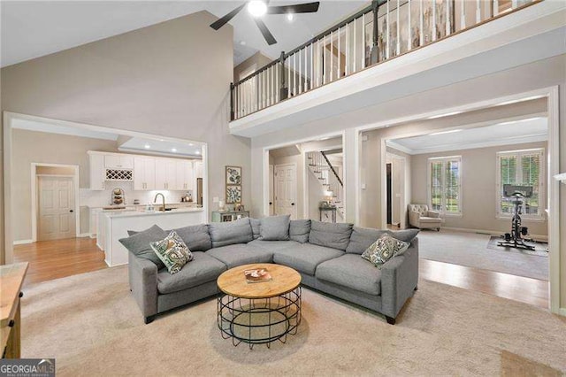 501 Avery Creek Pointe, Woodstock, GA 30188 - living room featuring stairway, light colored carpet, a ceiling fan, ornamental molding, and a towering ceiling
