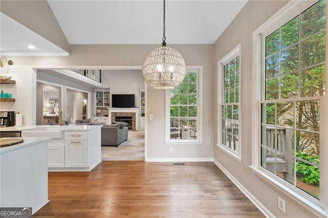 501 Avery Creek Pointe, Woodstock, GA 30188 - kitchen with a fireplace, white cabinets, healthy amount of natural light, a chandelier, and vaulted ceiling