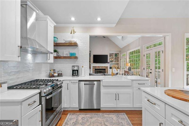 501 Avery Creek Pointe, Woodstock, GA 30188 - kitchen with stainless steel appliances, wall chimney range hood, a peninsula, light countertops, and light wood finished floors