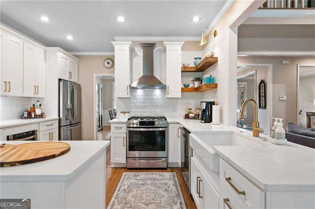 501 Avery Creek Pointe, Woodstock, GA 30188 - kitchen with stainless steel appliances, wall chimney exhaust hood, a peninsula, crown molding, and light wood-style flooring