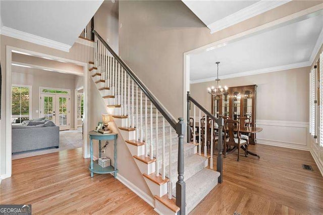501 Avery Creek Pointe, Woodstock, GA 30188 - stairway with french doors, healthy amount of natural light, a chandelier, wood finished floors, and crown molding