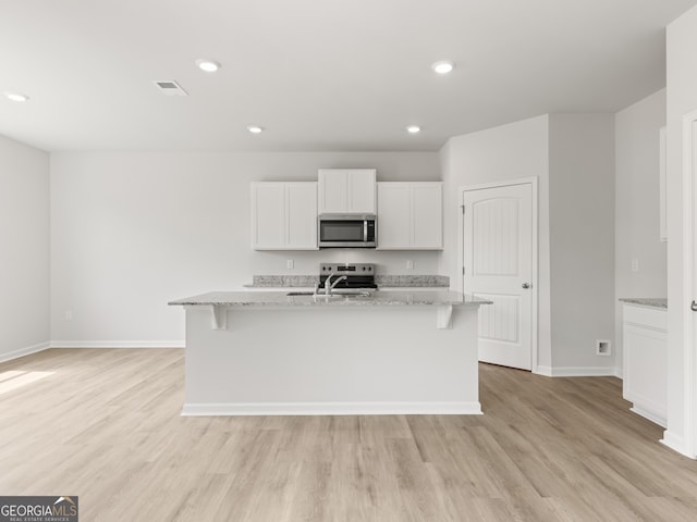 504 Oak View Ln, Dallas, GA 30157 - kitchen featuring stainless steel microwave, light wood finished floors, light stone countertops, white cabinetry, and recessed lighting