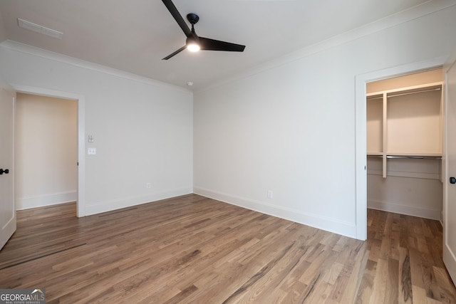 2164 James Aly, Atlanta, GA 30345 - unfurnished bedroom with crown molding, light wood-type flooring, a walk in closet, a closet, and ceiling fan