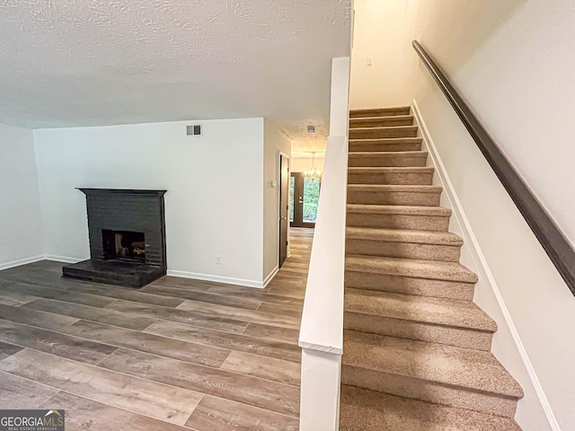 3150 Stratford Green Pl, Avondale Estates, GA 30002 - stairs with wood finished floors, a textured ceiling, a fireplace, and a chandelier
