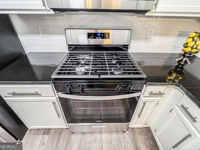 3150 Stratford Green Pl, Avondale Estates, GA 30002 - kitchen featuring stainless steel gas range oven, dark countertops, wood finished floors, and white cabinetry
