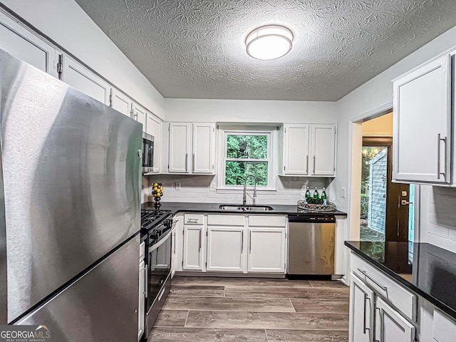 3150 Stratford Green Pl, Avondale Estates, GA 30002 - kitchen featuring appliances with stainless steel finishes, dark countertops, dark wood-style flooring, a textured ceiling, and white cabinets